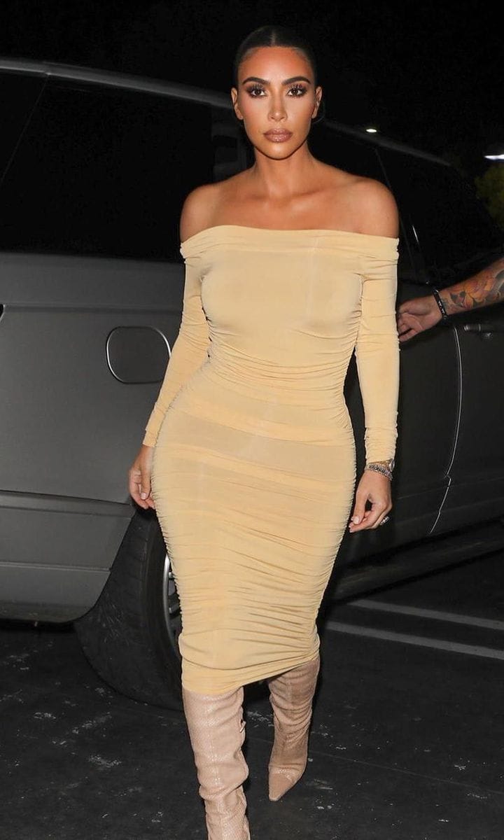 Kim Kardashian wearing an off-the-shoulder bodycon dress and knee-high boots