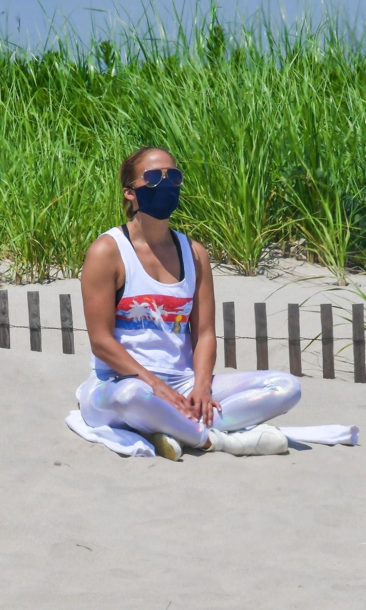 Jennifer Lopez at the beach in the Hamptons meditating with her mask on.