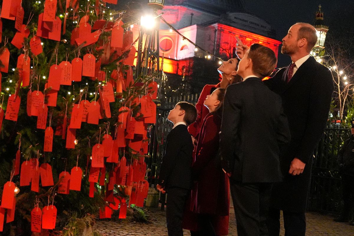 Britain's Prince William, Prince of Wales and Britain's Catherine, Princess of Wales look at messages on the Kindness Tree with Britain's Prince George of Wales (2R) Britain's Princess Charlotte of Wales (2L) and Britain's Prince Louis of Wales (L) before the "Together At Christmas" Carol Service" at Westminster Abbey in London on December 6, 2024. Britain's Catherine, Princess of Wales is organizing her traditional Christmas carol concert at Westminster Abbey on Friday evening, closing a painful year marked by her cancer, during which she will pay tribute to all those "who have gone through difficult times". (Photo by Jordan Pettitt / POOL / AFP) (Photo by JORDAN PETTITT/POOL/AFP via Getty Images)