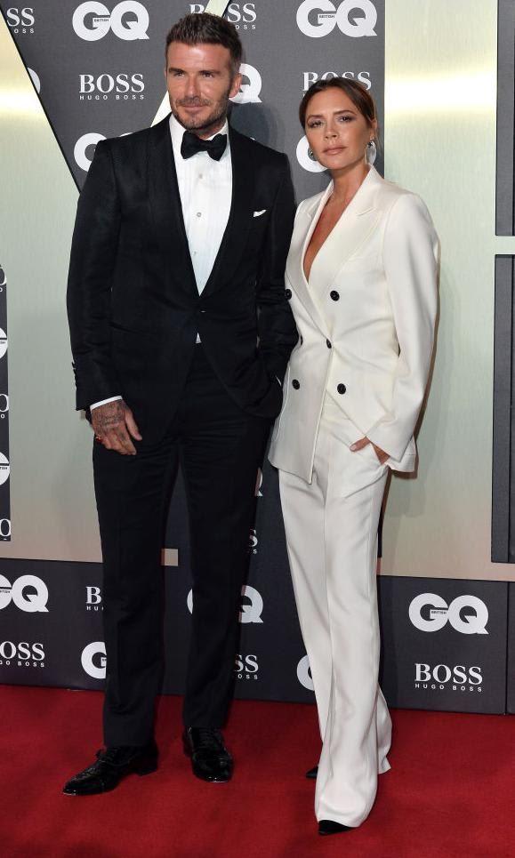 Victoria Beckham in a white pant suit and David Beckham in a black suit