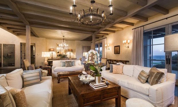 An iron, candleholder-style chandelier lights up a beautifully spacious living room, perfect for post-dinner chats and relaxation.