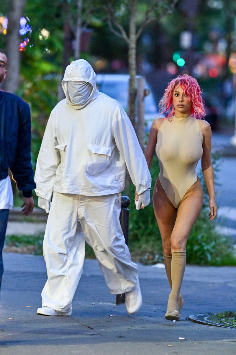 Kanye West and Bianca Censori exit from the Prototype fashion show during Paris Fashion Week. Kanye donned a full white outfit, while Bianca stood out with her striking pink hair. 