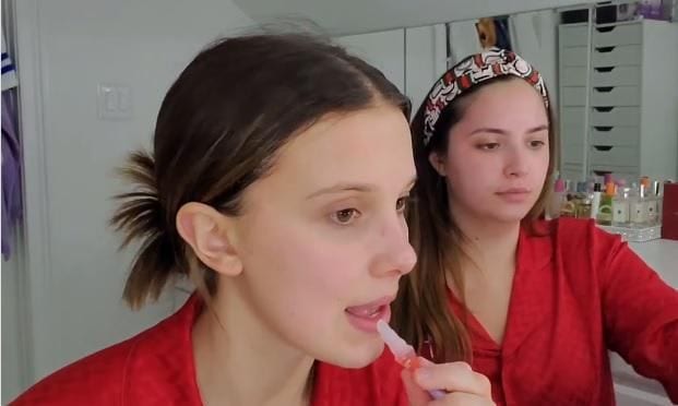 Millie Bobby Brown applying lip oil