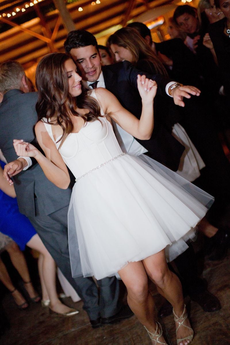  Soccer stars Alex Morgan and Servando Carrasco celebrate at their wedding reception at Rancho Dos Pueblos on December 31, 2014, in Santa Barbara, California. Morgan's reception dress "Little White Dress," pictured, was custom designed with her input by Amsale.  (Photo by Kamee June Photography/Handout/Getty Images)