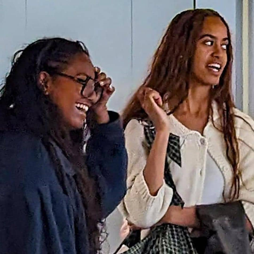 Malia and Sasha Obama laugh together as they wait to board their plane at LAX