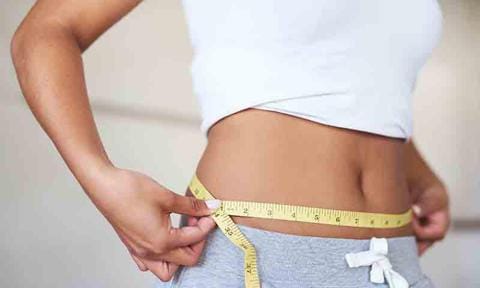 Mujer mide con cinta métrica su definido abdomen